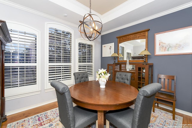 dining room featuring a tray ceiling, crown molding, a notable chandelier, light wood-style floors, and baseboards