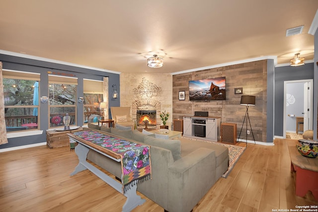 living room featuring a fireplace, visible vents, wood finished floors, and ornamental molding