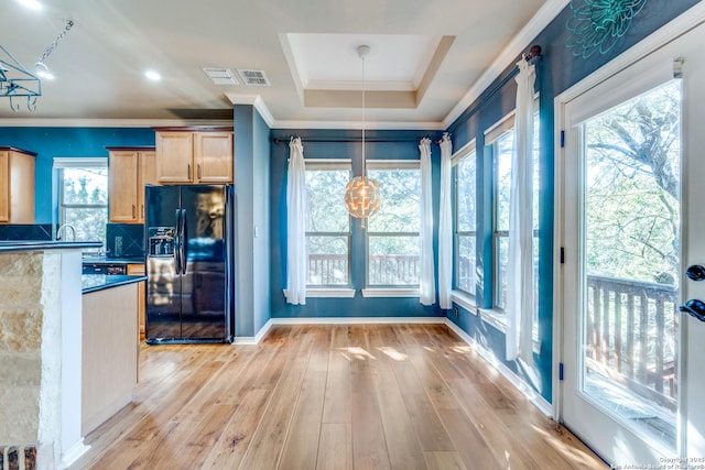 kitchen with black fridge with ice dispenser, light wood-style floors, light brown cabinetry, dark countertops, and pendant lighting