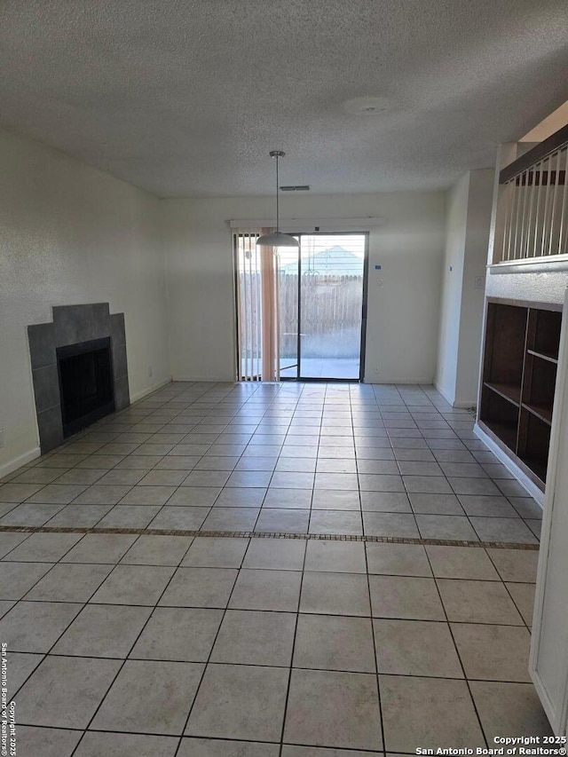 unfurnished living room with a fireplace, visible vents, a textured ceiling, and light tile patterned flooring