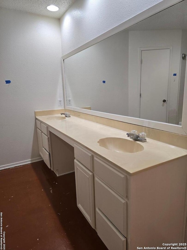 bathroom featuring a sink, a textured ceiling, baseboards, and double vanity