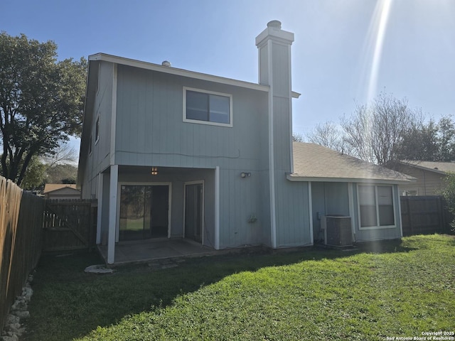 back of house with central AC unit, a lawn, and a fenced backyard