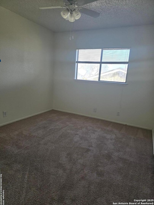 spare room with a ceiling fan, dark carpet, and a textured ceiling