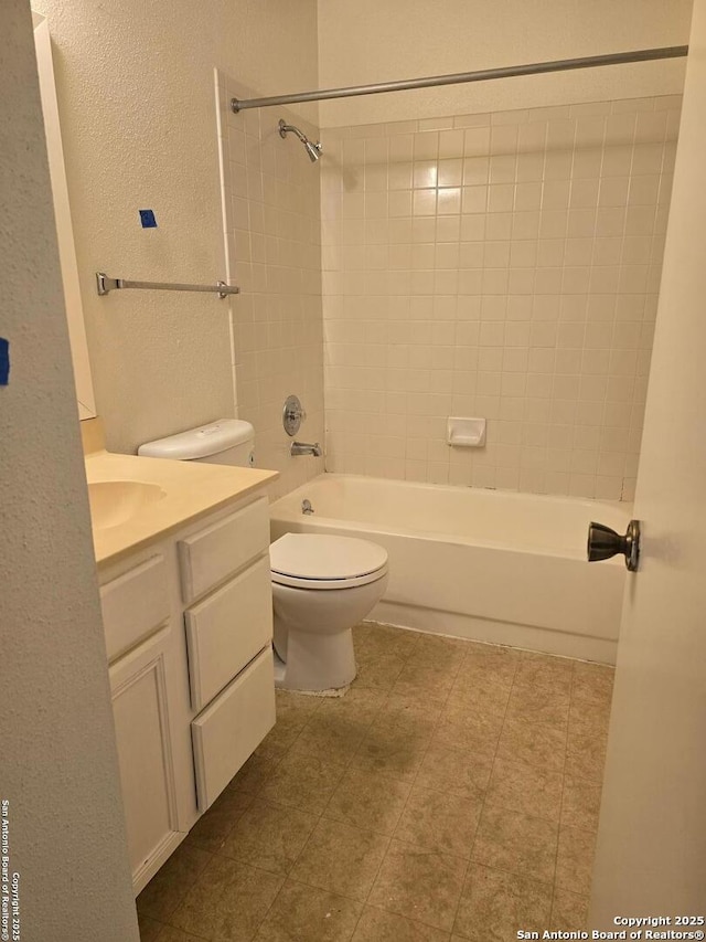 full bath featuring toilet, a textured wall, shower / washtub combination, and vanity