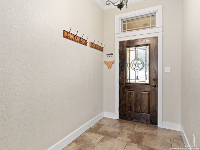 foyer entrance with ornamental molding and baseboards