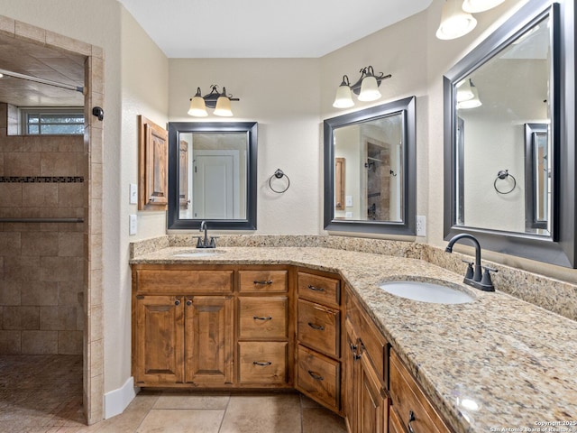 bathroom featuring double vanity, a tile shower, a sink, and tile patterned floors