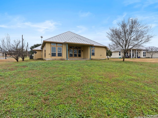back of house with metal roof, a yard, a standing seam roof, and stucco siding