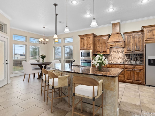 kitchen featuring an island with sink, a breakfast bar, stainless steel appliances, premium range hood, and a sink