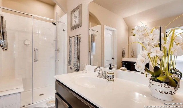 bathroom featuring lofted ceiling, a shower stall, and vanity