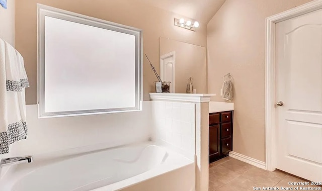 full bath with a garden tub, vanity, baseboards, and tile patterned floors