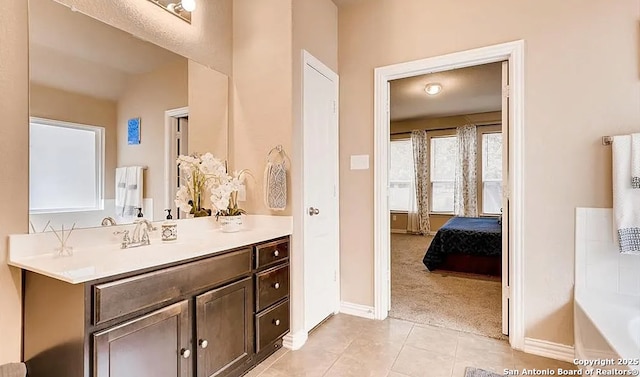 ensuite bathroom featuring tile patterned flooring, baseboards, vanity, and ensuite bath