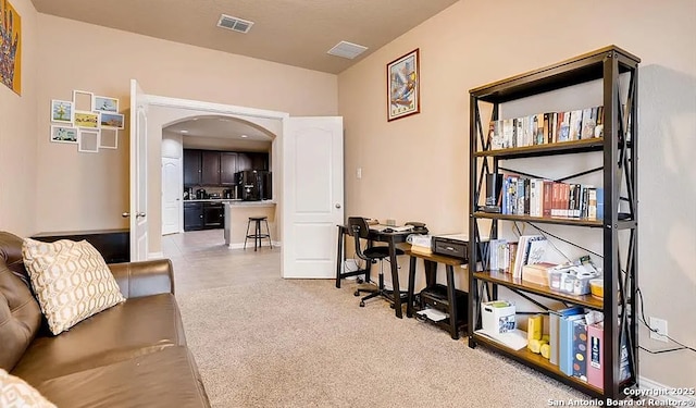 interior space with light colored carpet, arched walkways, visible vents, and baseboards