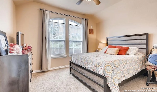 bedroom featuring light colored carpet, vaulted ceiling, baseboards, and ceiling fan