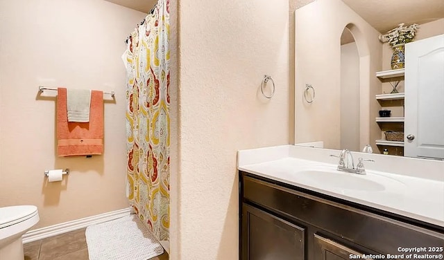 bathroom with tile patterned flooring, baseboards, vanity, and toilet