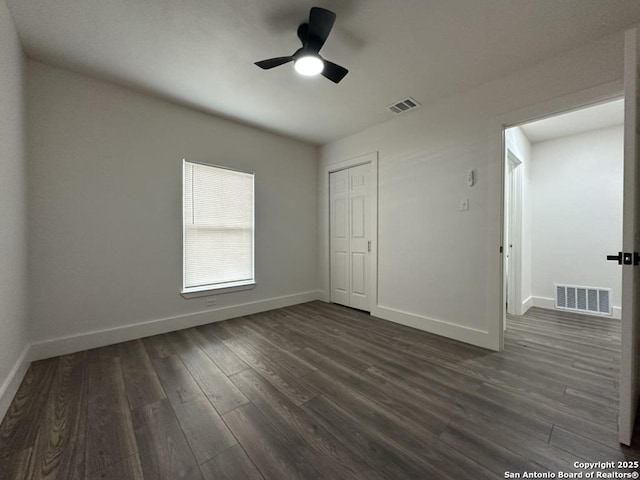 unfurnished bedroom with dark wood-style flooring, visible vents, and baseboards