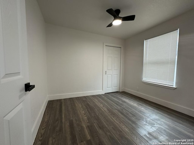 unfurnished bedroom with a ceiling fan, a closet, baseboards, and dark wood-style flooring