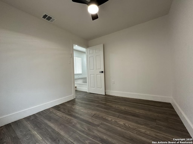 spare room with dark wood-style floors, ceiling fan, visible vents, and baseboards