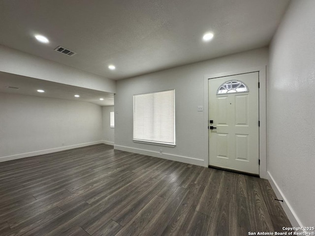 foyer entrance with dark wood-type flooring, visible vents, and baseboards