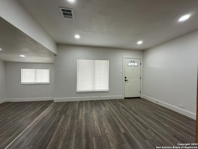 foyer with baseboards, visible vents, dark wood-style flooring, a textured ceiling, and recessed lighting