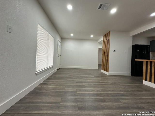 empty room with dark wood-style floors, recessed lighting, visible vents, and baseboards