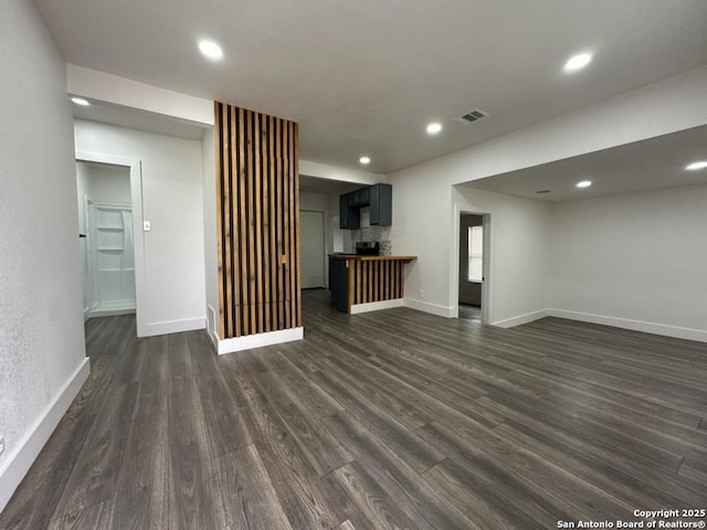 unfurnished living room with dark wood-style floors, baseboards, visible vents, and recessed lighting