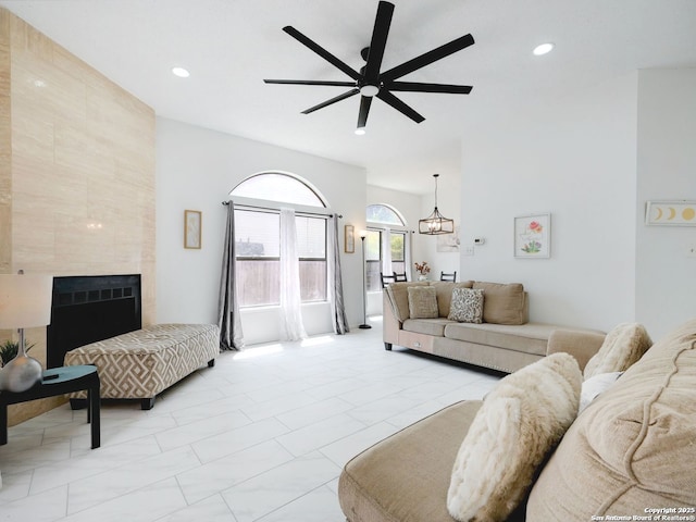 living room with marble finish floor, recessed lighting, ceiling fan with notable chandelier, and a tile fireplace