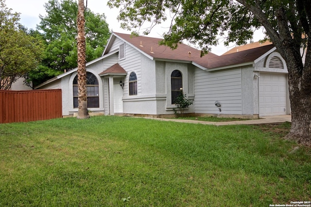 view of front of home featuring a front lawn, fence, and an attached garage