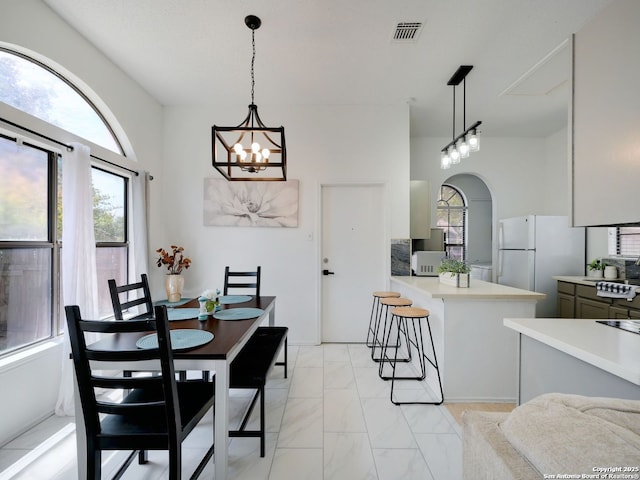 dining space with marble finish floor, visible vents, arched walkways, and a chandelier