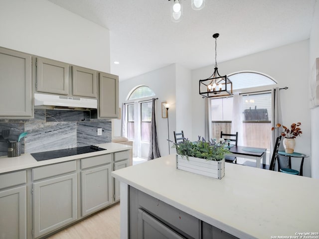 kitchen with under cabinet range hood, gray cabinets, black electric stovetop, and light countertops