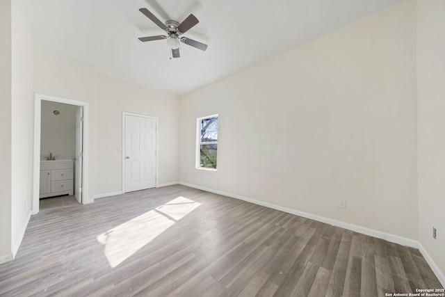 unfurnished bedroom featuring light wood-style floors, ceiling fan, baseboards, and ensuite bathroom