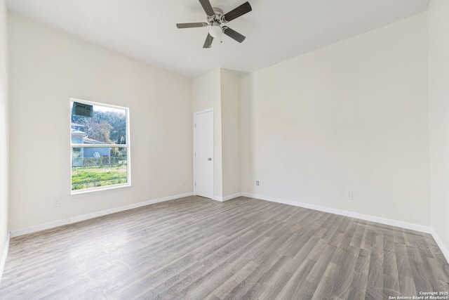 empty room with a ceiling fan, light wood-type flooring, and baseboards