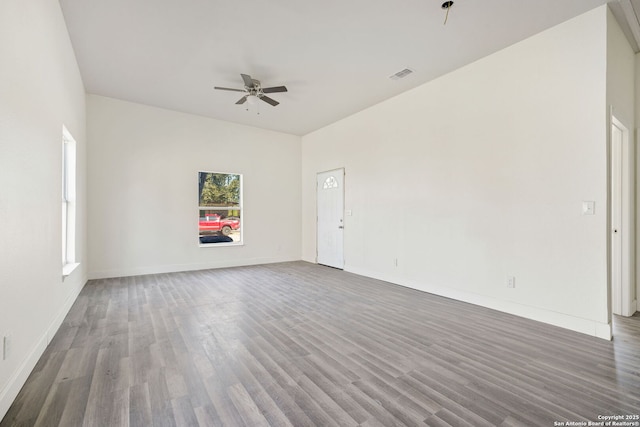 empty room featuring a ceiling fan, baseboards, visible vents, and dark wood-type flooring