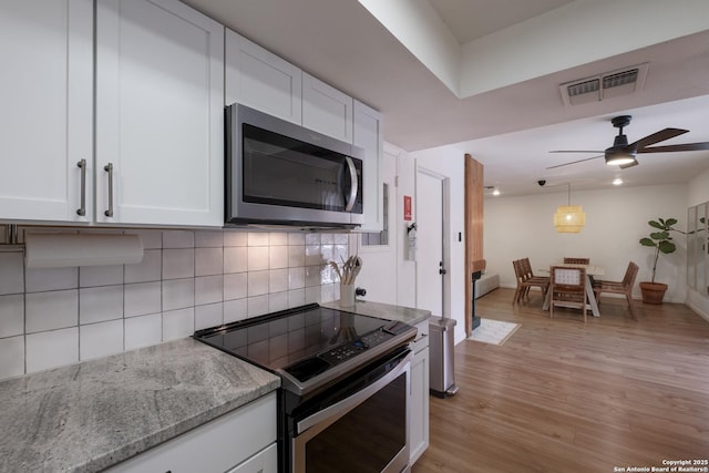 kitchen featuring stainless steel appliances, light stone countertops, visible vents, and white cabinets