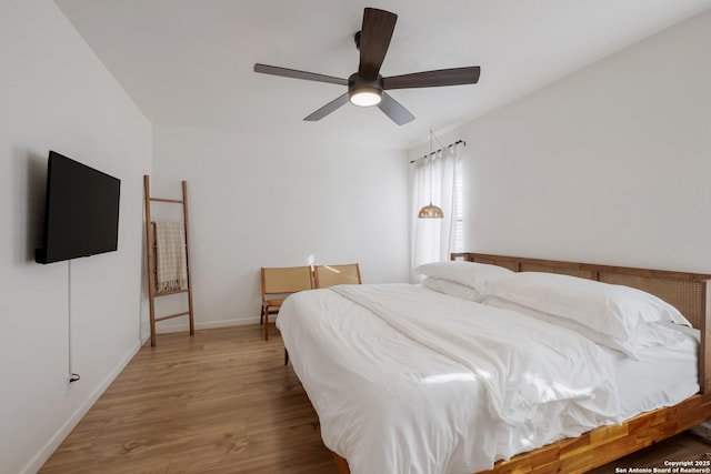 bedroom featuring ceiling fan, baseboards, and wood finished floors