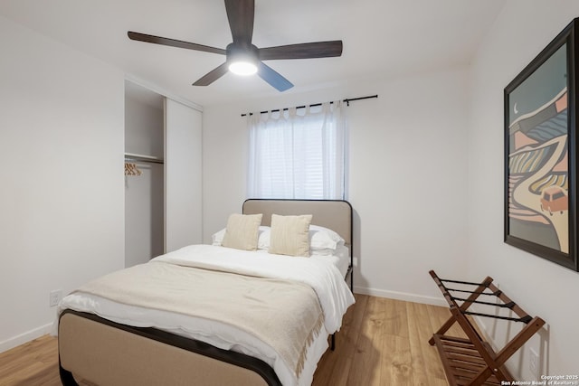 bedroom with a closet, ceiling fan, light wood-style flooring, and baseboards