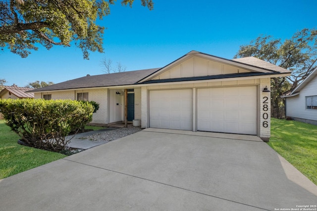 ranch-style home with a garage, brick siding, concrete driveway, a front lawn, and board and batten siding