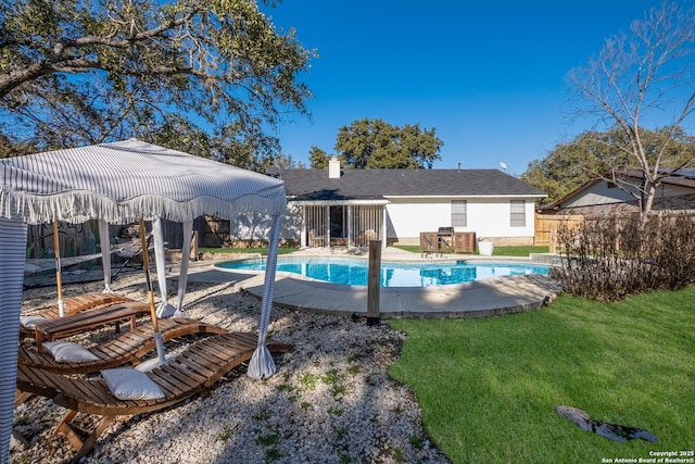 outdoor pool with fence and a lawn