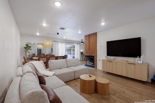 living room with light wood-type flooring, a fireplace, visible vents, and recessed lighting