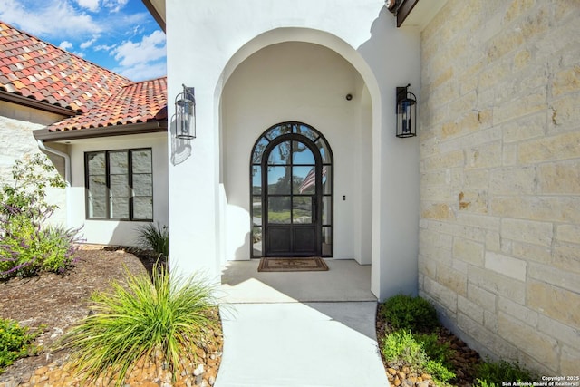 doorway to property featuring a tiled roof and stucco siding