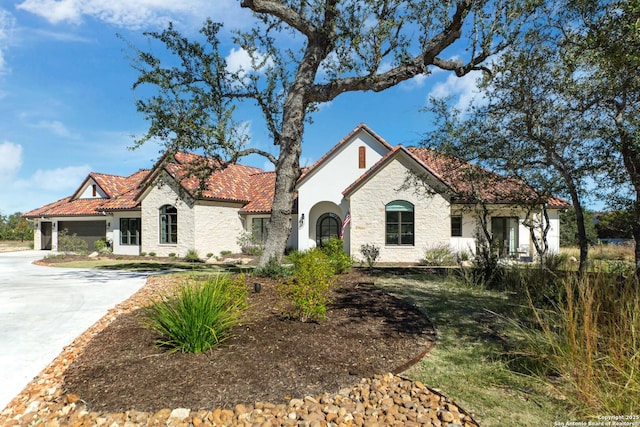 view of front of property featuring driveway, stone siding, a tile roof, and stucco siding