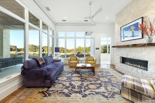 sunroom featuring a ceiling fan, visible vents, and a stone fireplace