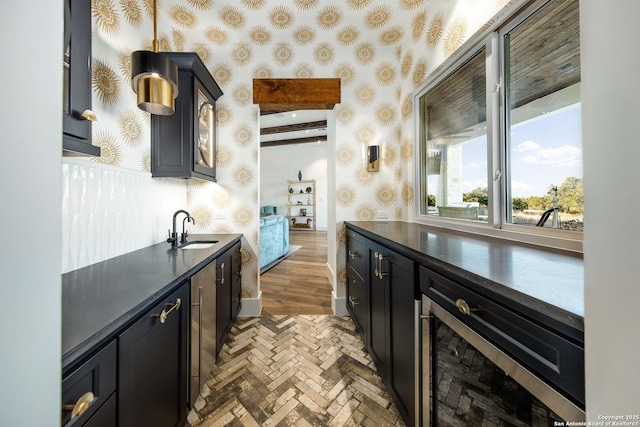 kitchen with brick floor, dark countertops, a sink, and wallpapered walls