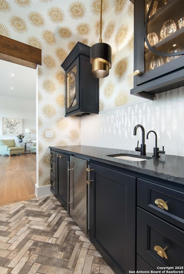 bar featuring a sink, baseboards, fridge, indoor wet bar, and wallpapered walls