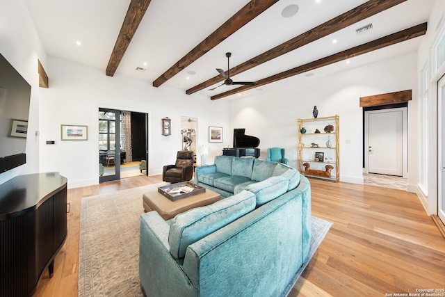 living area featuring light wood-style floors, baseboards, visible vents, and beamed ceiling