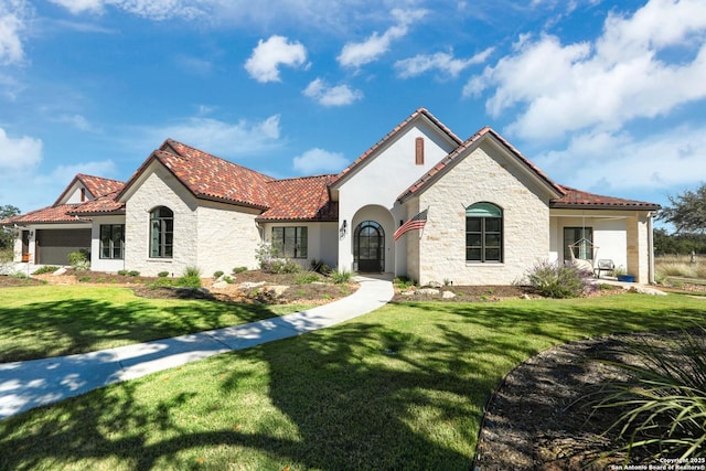 mediterranean / spanish-style house with a tiled roof, stone siding, a front yard, and stucco siding