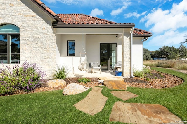 back of house with french doors, a tile roof, a patio, stucco siding, and a lawn