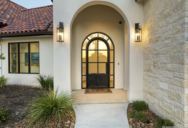 property entrance with a tile roof and stucco siding