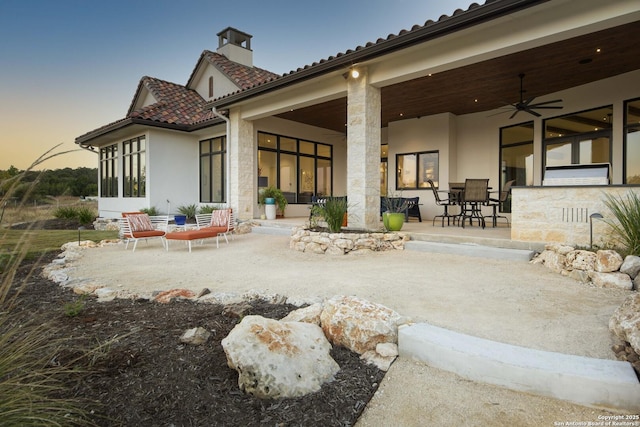 back of house featuring a tiled roof, a ceiling fan, a patio, and stucco siding