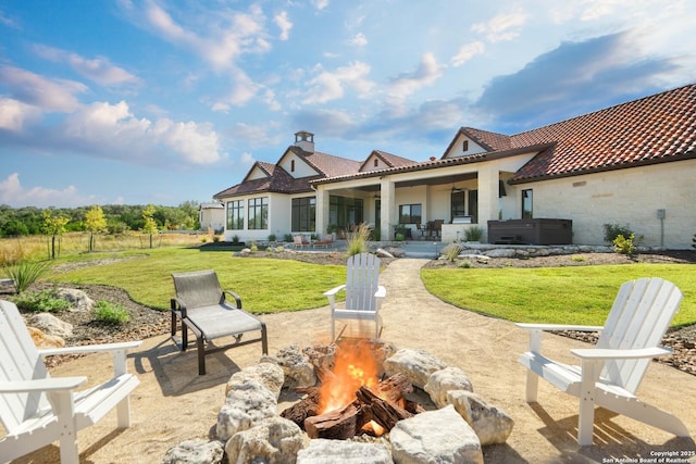 rear view of property with an outdoor fire pit, a patio area, a yard, and a tiled roof