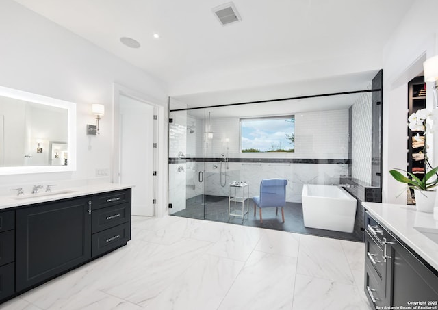 full bath featuring two vanities, a sink, marble finish floor, a soaking tub, and a shower stall